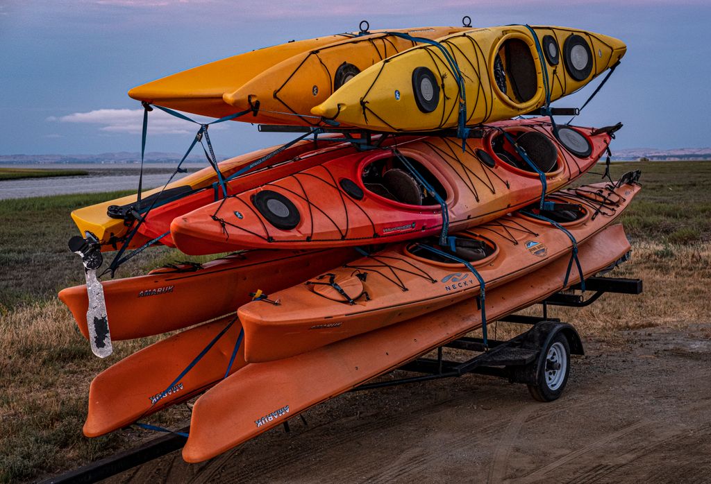 Colorful kayaks stacked on a trailer ready for adventure in a scenic outdoor setting.